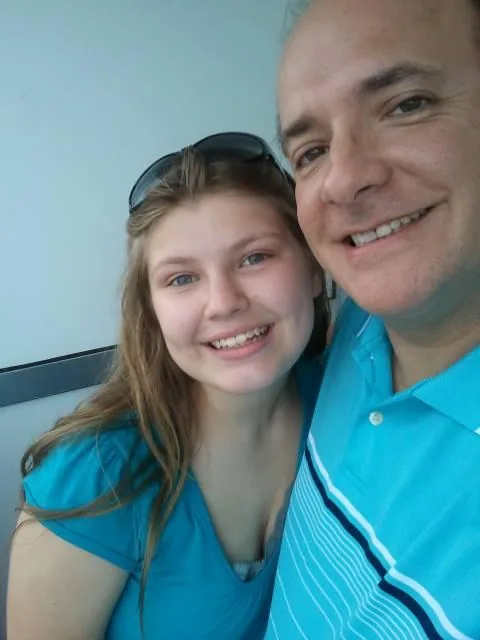 Man and young girl smiling at camera, both wearing blue shirts